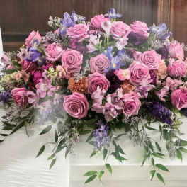 Large pink and purple floral casket spray with roses and lilies