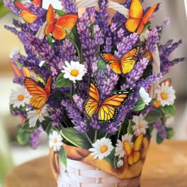 Purple flowers in a woven basket with butterfly decorations and white daisies
