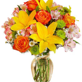 Bouquet of yellow lilies and orange roses in a glass vase