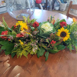 Low floral centerpiece with sunflowers, roses, and lilies on a table