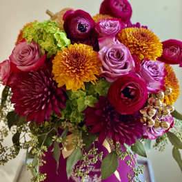 Bright mixed bouquet with pink, purple, and yellow blooms in a magenta box