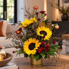 Sunflower arrangement in a gold vase with burgundy accents