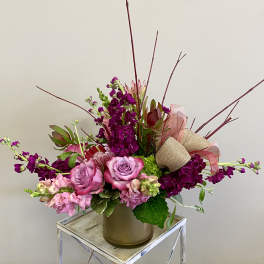 Pink and purple floral arrangement in a vase with ribbon accents