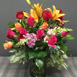 Mixed bouquet of roses, lilies, and snapdragons in a glass vase