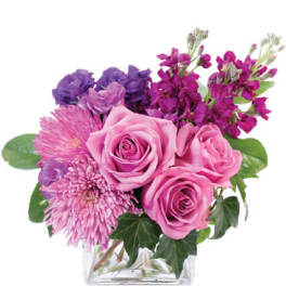 Pink and purple flower arrangement in a clear square vase