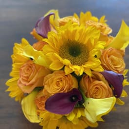 Bouquet of sunflowers, orange roses, and purple calla lilies