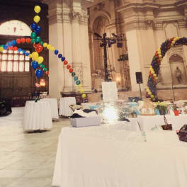Colorful balloon arches in a large hall with tables below