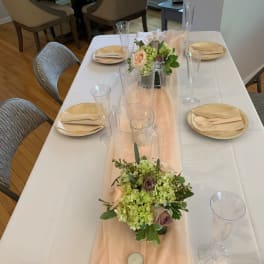 Low floral centerpieces on a set dining table with blush and green blooms