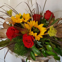 Arrangement of red roses and yellow sunflowers in a low container
