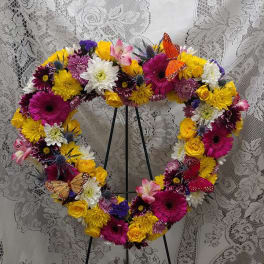 Heart-shaped floral wreath with bright mixed blooms on a stand