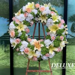 Heart-shaped floral wreath with pink roses, white hydrangeas, and yellow lilies on an easel