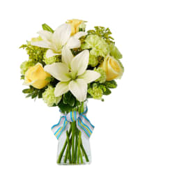 Bouquet of white lilies and yellow roses in a glass vase with a striped ribbon