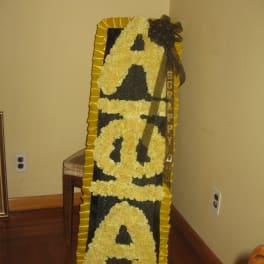 Tall floral standing tribute with yellow flowers spelling "SORRY"