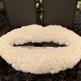 Large white floral wreath laid flat on chairs