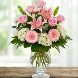 Pink roses, lilies, gerbera daisies, and white hydrangeas in a glass vase