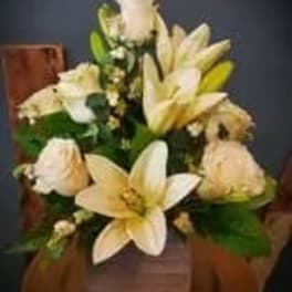 Cream lilies and roses arranged in a wooden basket