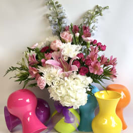 Mixed pink and white flower arrangement in colorful vases
