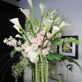 Tall arrangement of white calla lilies and pale pink roses in a vase