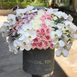 Pink and white roses with white orchids in a black hat box