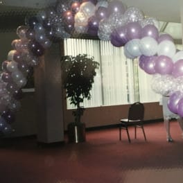 Purple and white balloon arch in an indoor room