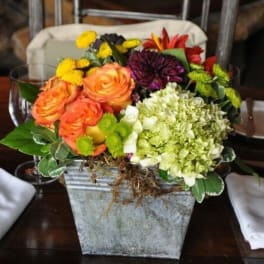 Mixed bouquet in a square metal container with orange roses and hydrangea