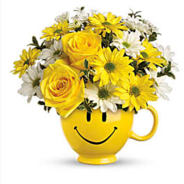 Yellow and white flowers arranged in a smiley-face mug