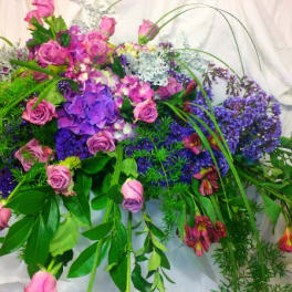 Large arrangement of pink and purple flowers with cascading greenery
