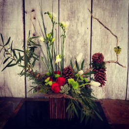 Arrangement of red roses, white blooms, and pinecones in a rustic container