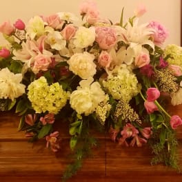 Casket spray with pink and white flowers and trailing greenery