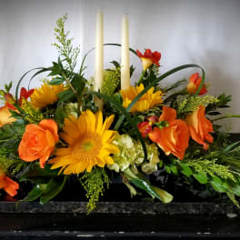 Orange and yellow floral centerpiece with tall white candles