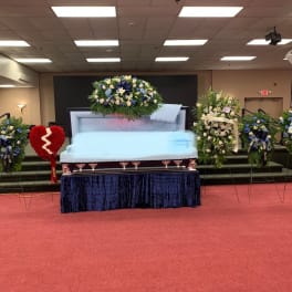 Casket surrounded by blue and white funeral flower sprays