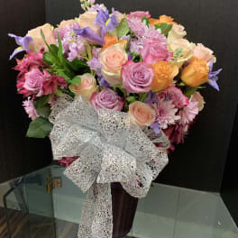 Mixed bouquet of pastel roses, irises, and chrysanthemums with a silver bow