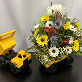 Bouquet in a yellow toy dump truck with white and yellow flowers