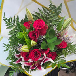 Bouquet of red roses and pink lilies with fern foliage