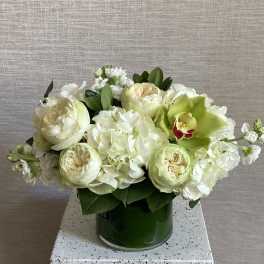 White and pale green floral arrangement in a green vase
