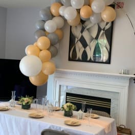 Balloon garland in white, gray, and gold over a decorated table