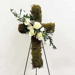 Moss-covered cross with white flowers on a stand