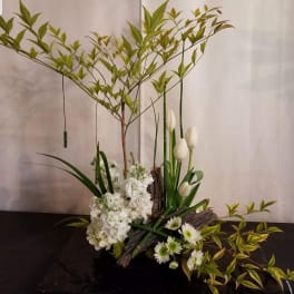 White floral arrangement with tulips and daisies in a low container