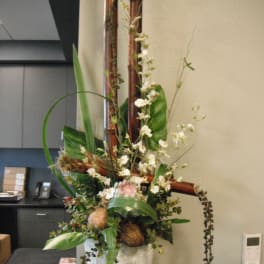Tall floral arrangement in a white textured pot with white blossoms and greenery