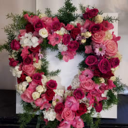 Heart-shaped floral wreath of pink and white roses with greenery
