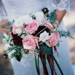 Bride holding a bouquet of pink and white roses with greenery
