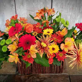Bright mixed flower arrangement in a rectangular wooden basket