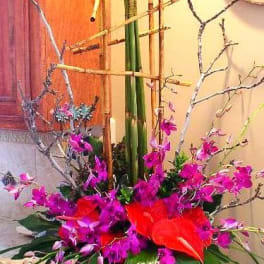 Tall red and purple floral arrangement in a dark vase