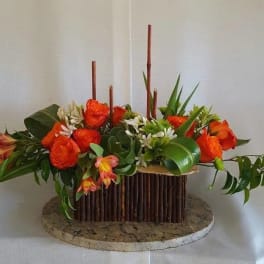 Orange roses arranged in a low rectangular centerpiece with greenery