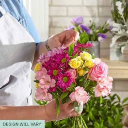 Handheld bouquet of pink, yellow, and purple flowers