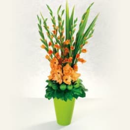 Orange flowers in a lime green vase with tall green leaves