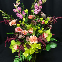 Mixed bouquet of pink and green flowers in a glass vase with a ribbon