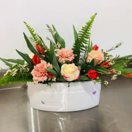 Mixed bouquet of roses, tulips, and carnations in a white container