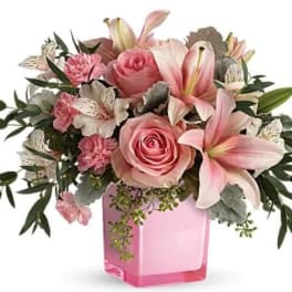 Pink roses and lilies arranged in a pink glass vase