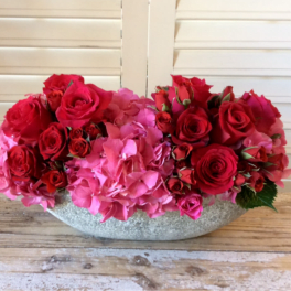 Red roses and pink hydrangeas in a low gray bowl